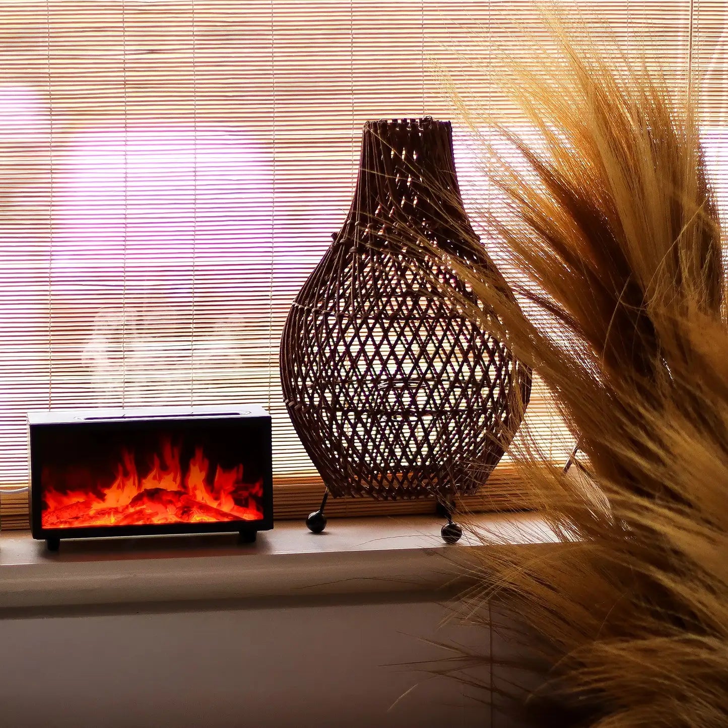 Woven decorative vase and small electric fireplace on a windowsill with natural light filtering through blinds.